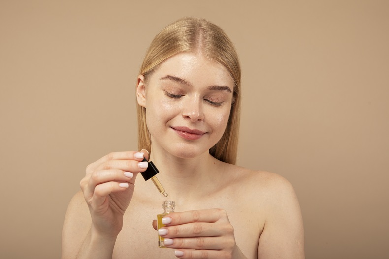 Kobieta aplikuje olej naturalny do twarzy